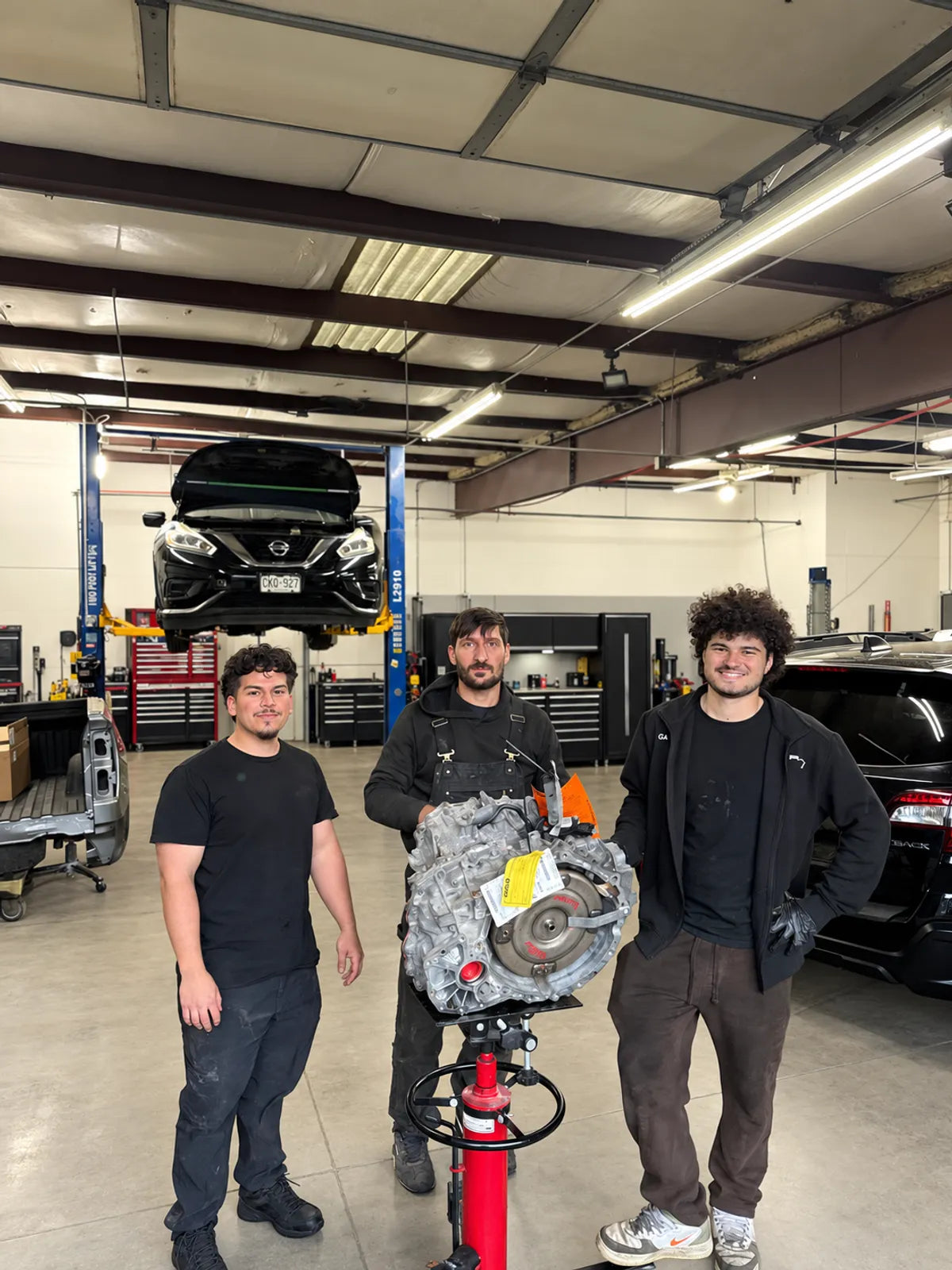 Three AYRD team members with a transmission in the workshop